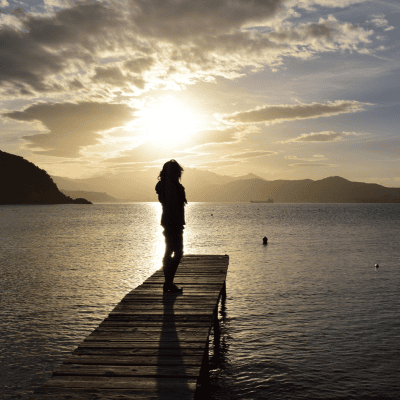 Woman standing on a pier at sunset.